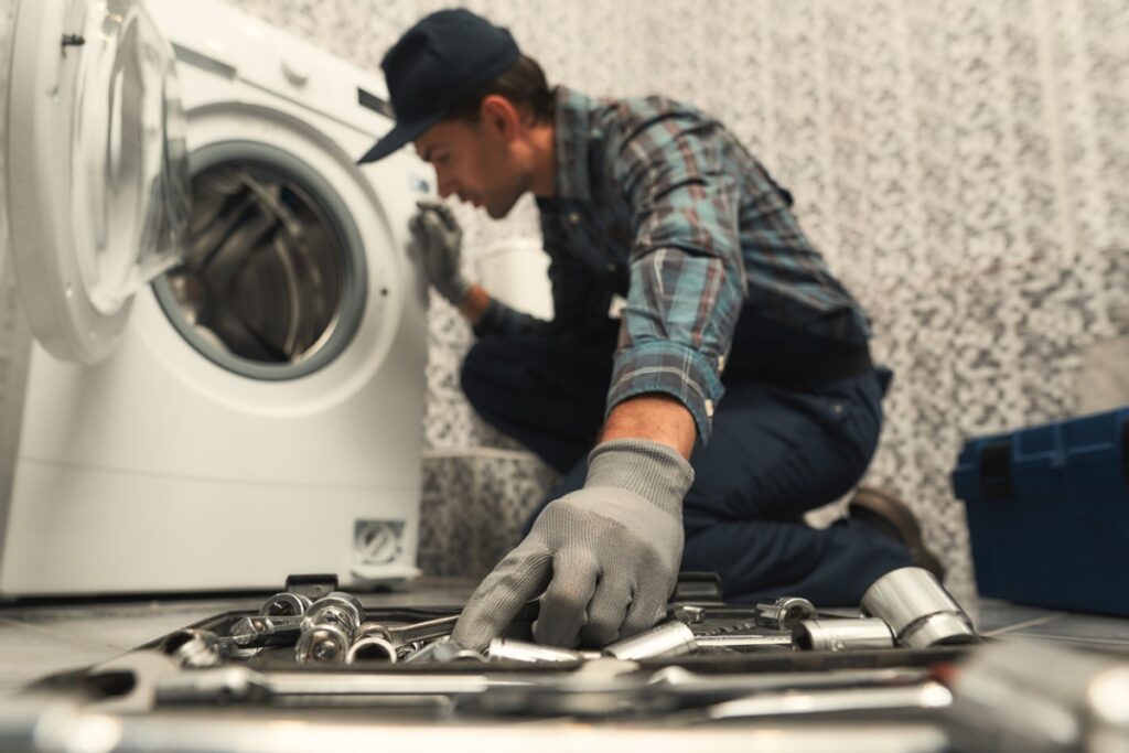 choosing-the-right-tool-plumber-repairing-washing-machine-picture-id1170038003